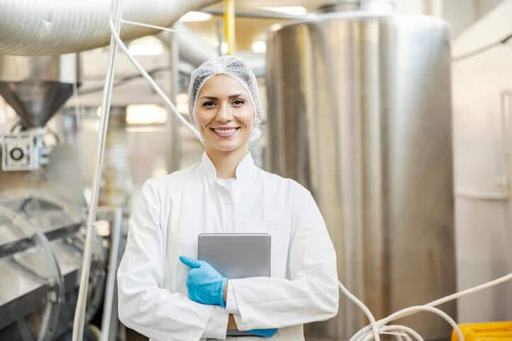 Food safety professional at a food production facility smiling at camera