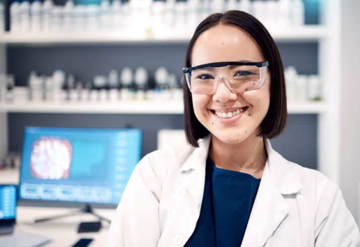 A scientist working in a lab wearing protective glasses and a lab coat in pharmaceutical school.