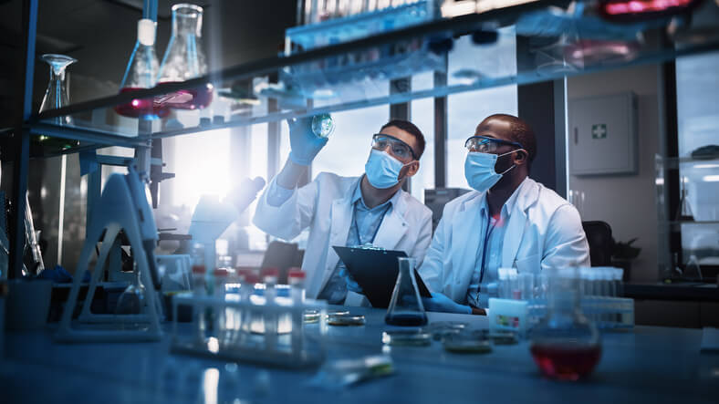 Two scientists using a microscope in a laboratory during pharmaceutical research training
