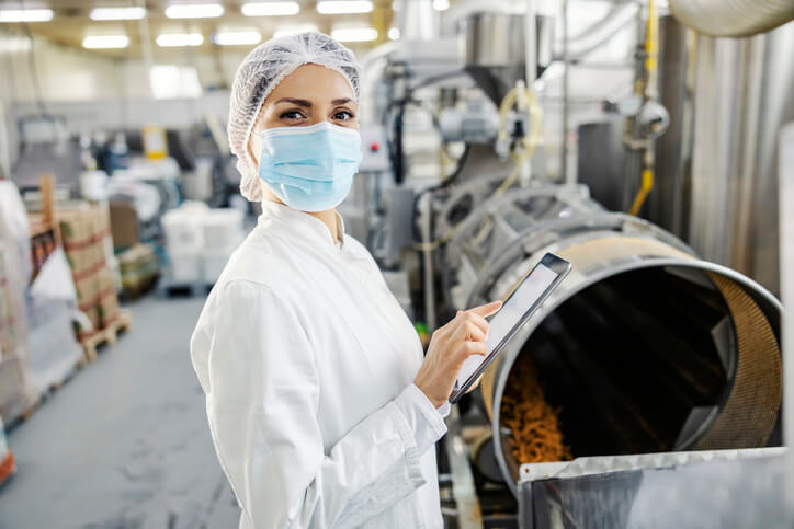 A production associate monitoring food processing in a factory after completing her food safety training