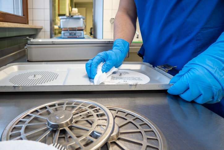 A pharmaceutical professional cleaning instrument containers with a cleaning cloth after pharmaceutical training
